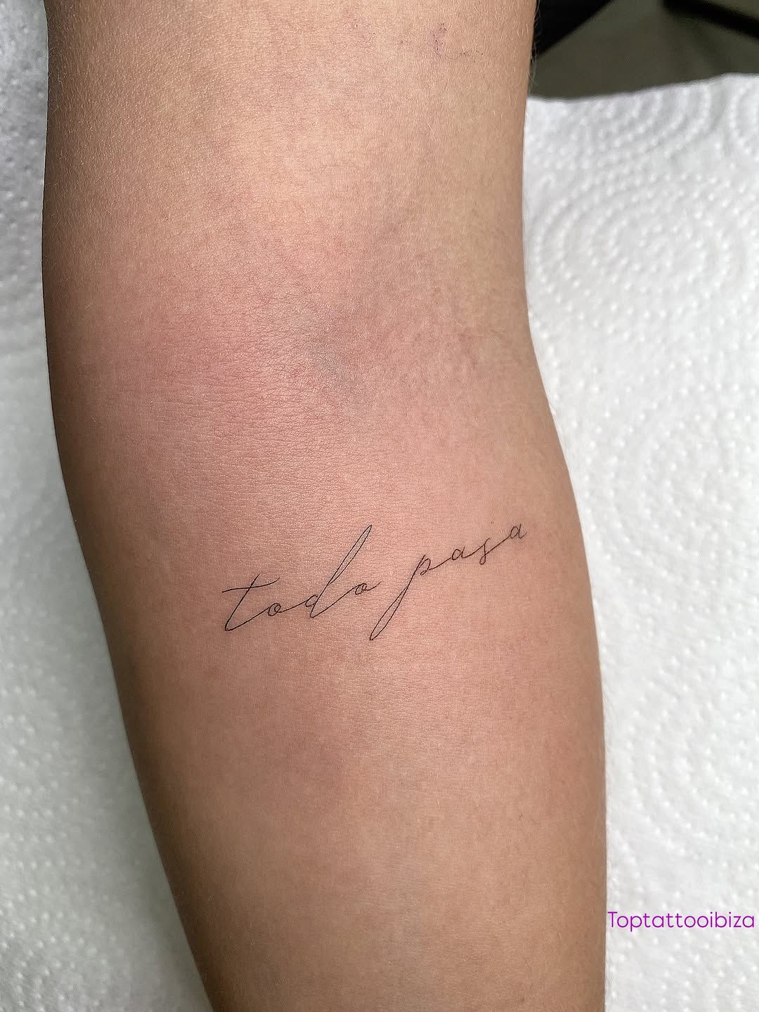 Delicate script tattoo reading 'todo pasa' on a calf